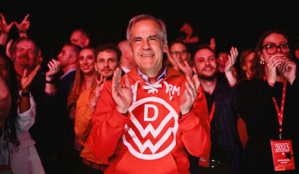 Canada's Prime Minister Mark Carney applauds as he stands next to supporters during an event at the Liberal Party election night headquarters.