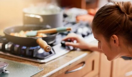 Wanita Memasak Menyesuaikan Kompor Dapur Gas